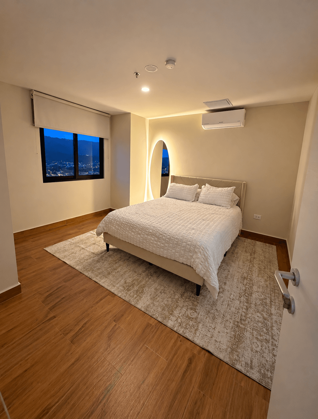 Habitación principal con cama, aire acondicionado y espejo iluminado