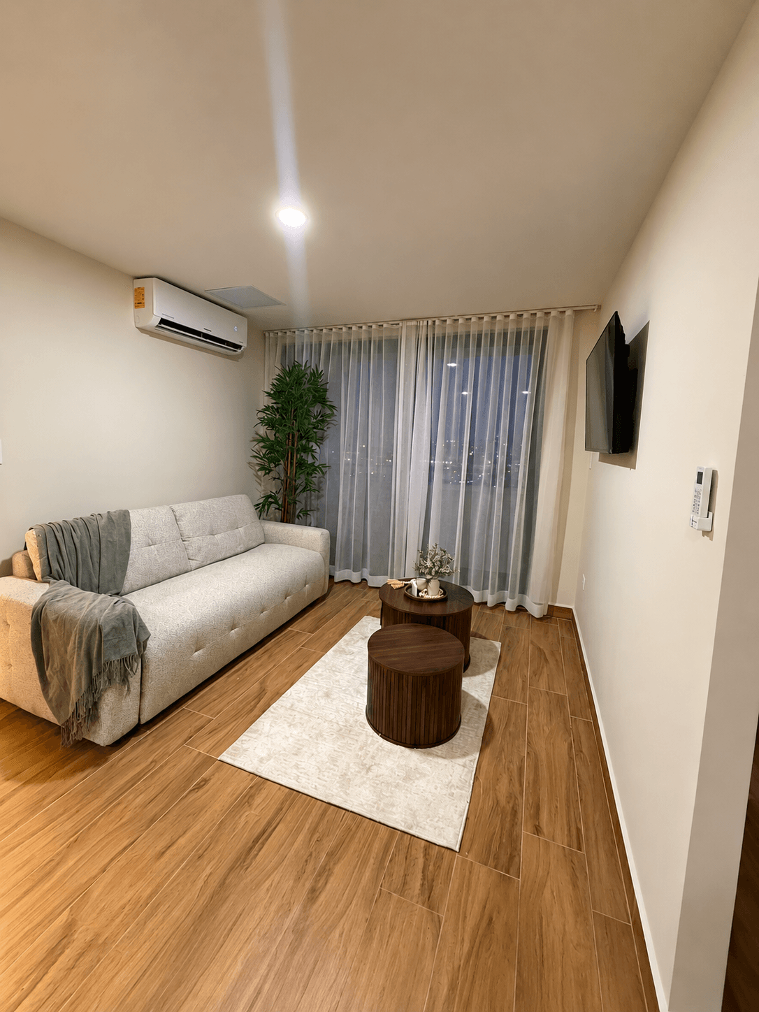 Sala amueblada con aire acondicionado, TV y cortinas