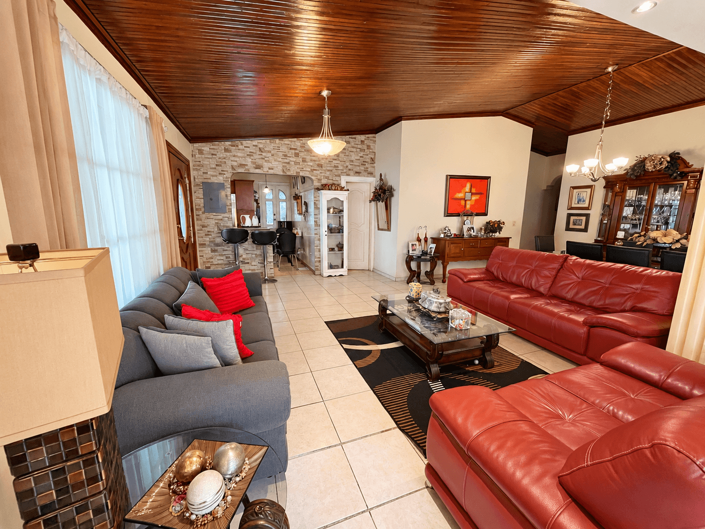 Sala con sofás de cuero, ventanales y cortinas hacia el jardín