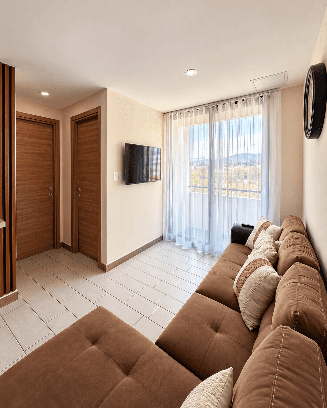 Sala amueblada con sofá, TV y cortinas hacia la vista de la montaña