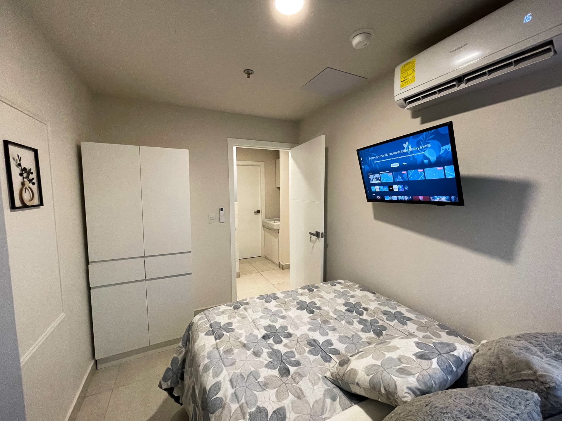 Habitación con cama, clóset, aire acondicionado y TV