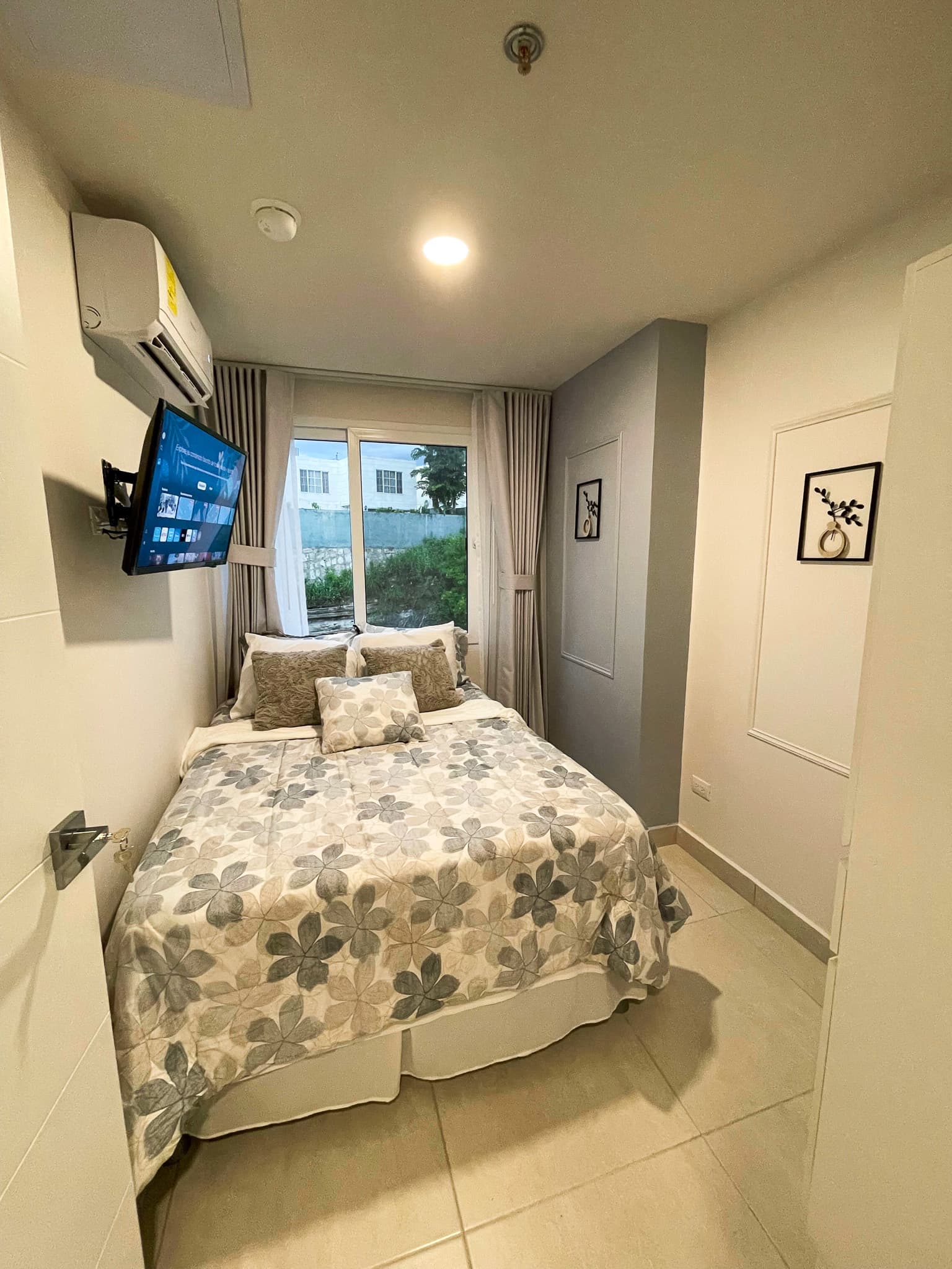 Habitación con cama, ventana, aire acondicionado y TV