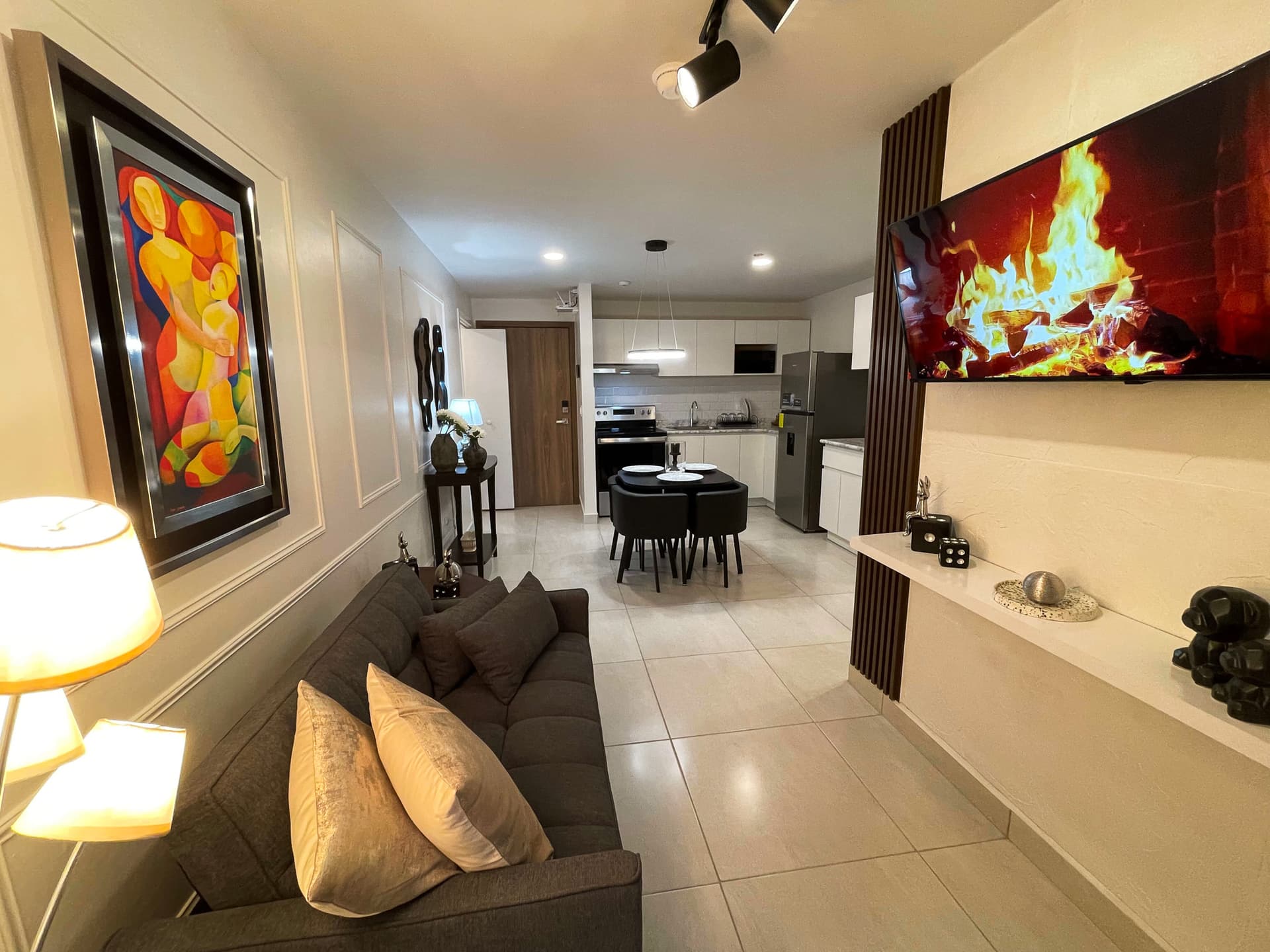 Sala amueblada con sofá y TV, comedor y cocina al fondo