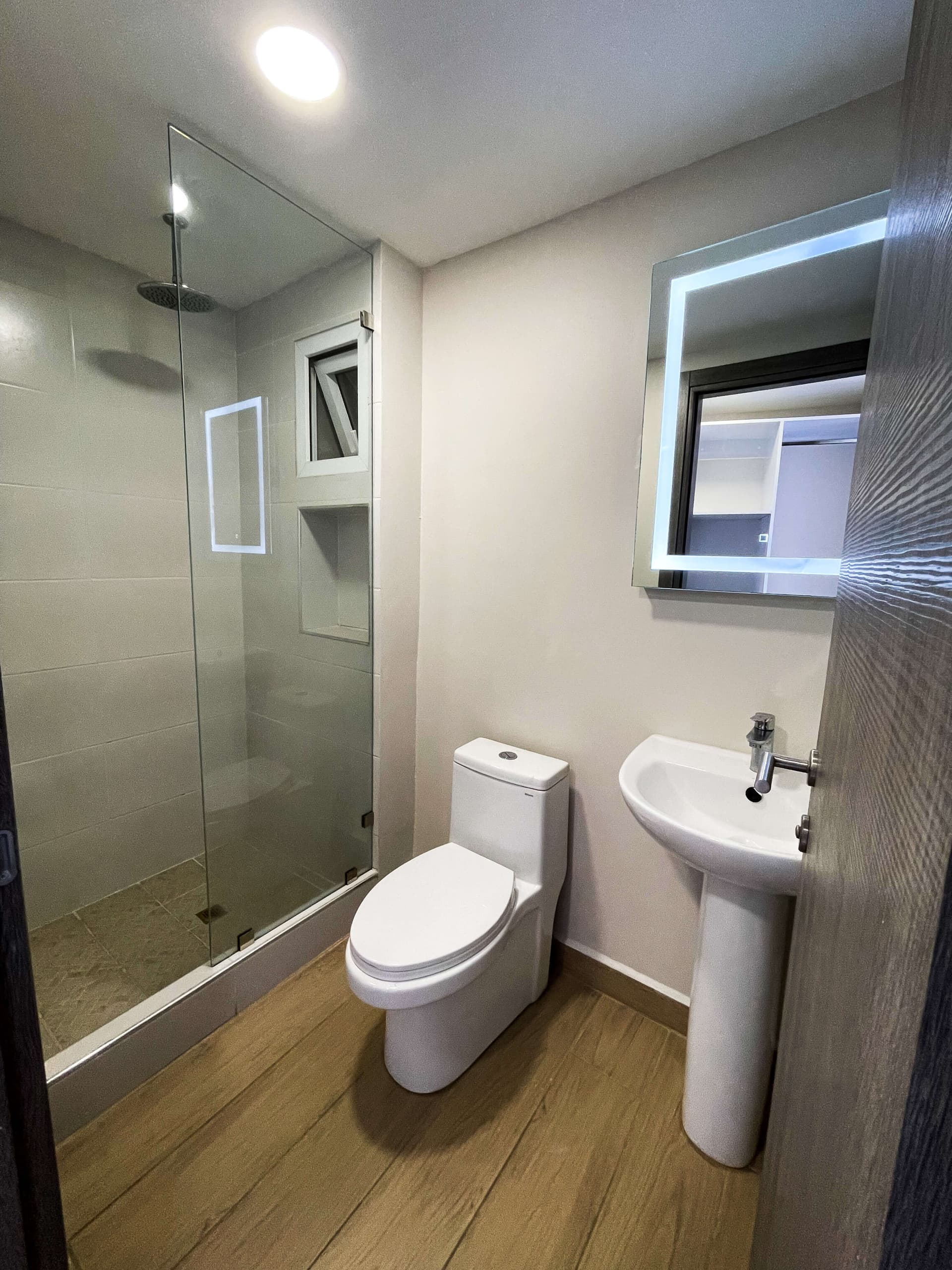 Baño con ducha, inodoro y lavamanos con espejo iluminado