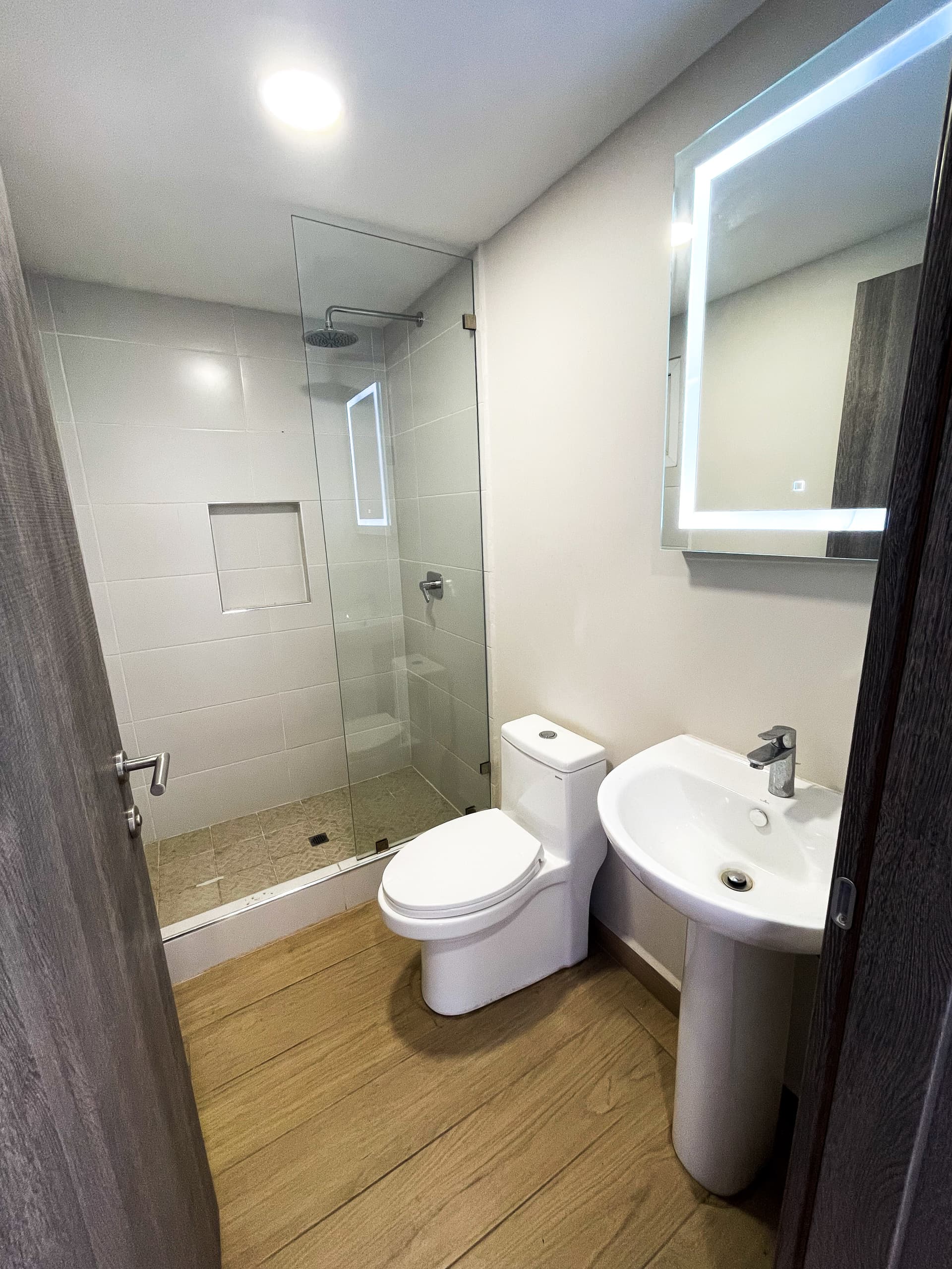 Segundo baño con ducha, inodoro y lavamanos con espejo iluminado